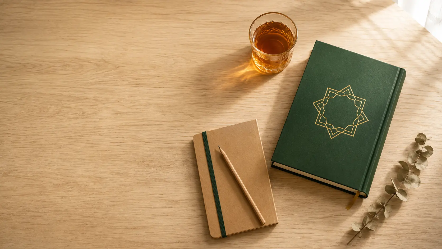 Mesa de madeira clara com livro de capa verde e detalhes dourados, copo de chá âmbar e caderno - composição minimalista evocando reflexão, propósito e espiritualidade do Islam